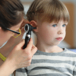 A woman examines a child's ear with a microphone, highlighting signs of an ear infection and early symptom detection.