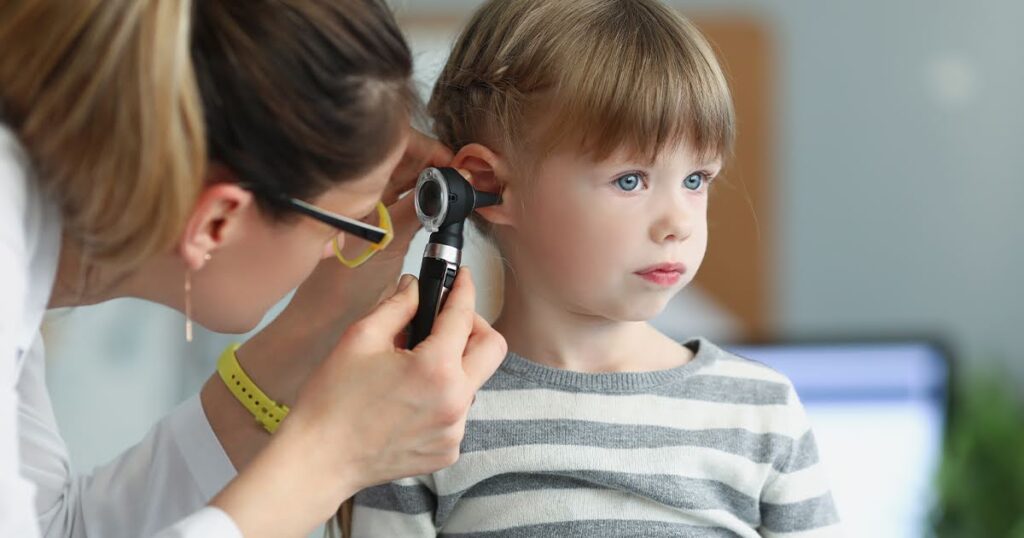 A woman examines a child's ear with a microphone, highlighting signs of an ear infection and early symptom detection.