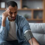 Man feeling dizzy while checking high blood pressure at home.