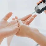 Doctor performing a finger-prick blood glucose test for diabetes.
