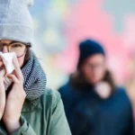 Person in winter gear blowing their nose, illustrating walking pneumonia symptoms