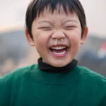Happy child laughing with visible green and yellow nasal mucus