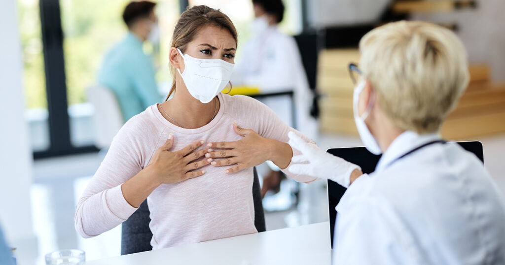 A woman in a mask and gloves speaks with a doctor in an ER setting in Texas.