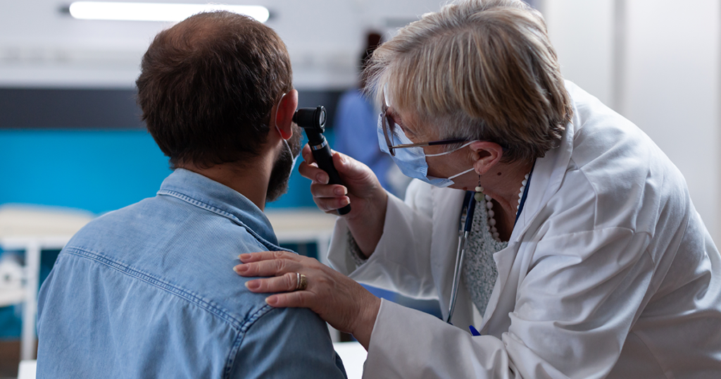 Doctor examining a patient’s ear with an otoscope.