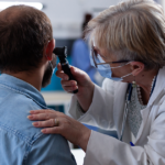 Doctor examining a patient’s ear with an otoscope.